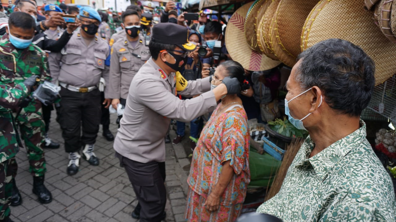 Kapolda Jatim Memakaikan Masker Secara Langsung Ke Masyarakat Saat Pembagian Masker Di Pasar Simo