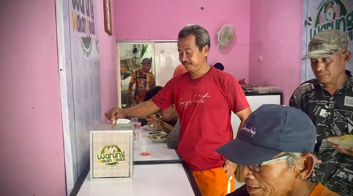 Salah satu pembeli sedang membayar makanan pada kotak yang telah disediakan oleh pemilik warung. Foto : suarasatu.com