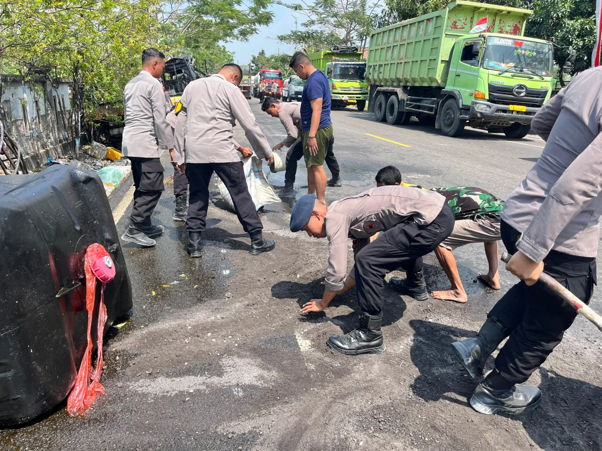 Pasukan Brimob kompi 3 Batalyon C bantu bersihkan tumpahan minyak di jalan. Foto : suarasatu.com